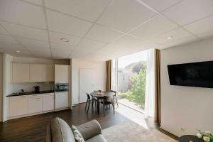 a living room with a kitchen and a table with chairs at Los Lorentes Hotel Bern Airport in Belp