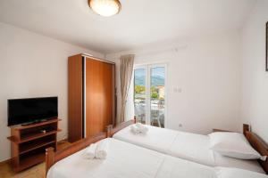 two beds in a room with a tv and a window at Sunset Studio Apartments Bjelila in Tivat