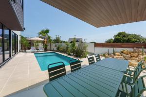 a patio with a blue table and chairs next to a swimming pool at 2026年8月新築,海直結!!ビーチフロント,オーシャンビュー,プール,サウナ付きヴィラ---Taito Pool EDGE--- in Chōjamachi
