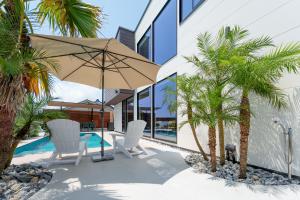 a patio with two chairs and an umbrella and palm trees at 2026年8月新築,海直結!!ビーチフロント,オーシャンビュー,プール,サウナ付きヴィラ---Taito Pool EDGE--- in Chōjamachi +98 photos