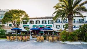 a group of chairs and umbrellas in front of a hotel at Hotel Sis Pins in Port de Pollensa
