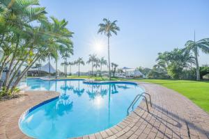 a swimming pool with palm trees and a golf course at Breakers Resort 130 Umhlanga Beachfront in Durban