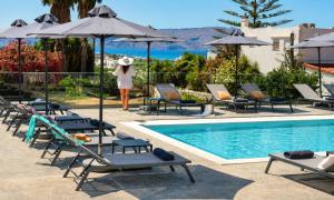 a woman standing next to a swimming pool with chairs and umbrellas at Pranvera Villa Sea View & Pool in Dhrámia
