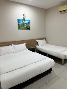 two beds in a room with white walls at Hotel Lean Fatt in Ipoh