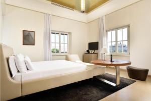 a white bedroom with a bed and a table at Palazzo Montemartini Rome, A Radisson Collection Hotel in Rome