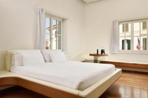 a white bedroom with a large bed and two windows at Palazzo Montemartini Rome, A Radisson Collection Hotel in Rome