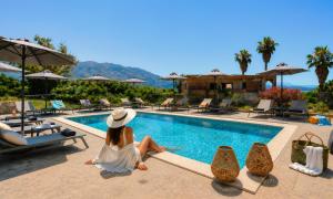 a woman in a white dress sitting next to a swimming pool at Pranvera Villa Sea View & Pool in Dhrámia