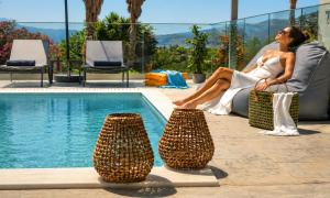 a woman sitting in a chair next to a swimming pool at Pranvera Villa Sea View & Pool in Dhrámia
