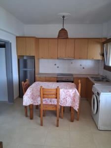 a kitchen with a table and two chairs and a refrigerator at Porto Beach Apartment in Makry Gialos