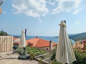 a couple of white umbrellas sitting on a patio at Apartments Zahtila - Pina in Rabac