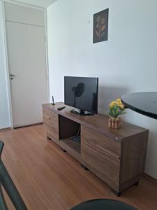 a living room with a television on a wooden cabinet at Apto Oeste simples Santa cruz in Santa Cruz