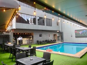 a pool in a building with tables and chairs at Emirates Star Hotel & Suites in Asaba