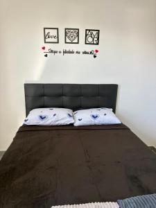 a bed with a black headboard and three pictures on the wall at Apartamento com vista e privacidade , ideal para casais , próximo da praia in Rio de Janeiro