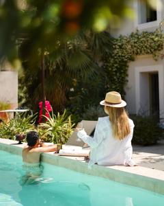 a woman in a hat sitting in a swimming pool at MARCELLE EN CAMARGUE - intra muros - piscine et jardin - petit déjeuner compris in Aigues-Mortes