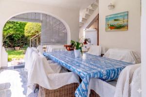 a dining room with white chairs and a blue and white table at Beachfront Luxury Villa Letizia - Sea View Terraces & Green Solar Energy in Quartu SantʼElena