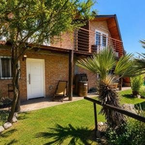 a brick house with a white door and a yard at Cabañas Caranday in Capilla del Monte