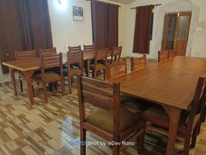 a dining room with wooden tables and chairs at Dayara resort in Bhatwāri