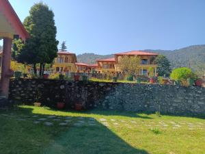 a stone wall in front of a house at Dayara resort in Bhatwāri