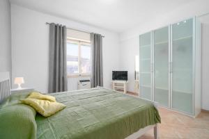 a bedroom with a green bed and a television at Excelsior - Venturina Terme in Venturina Terme