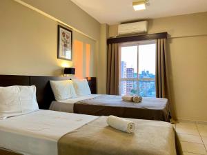 a hotel room with two beds and a window at Flat em Frente a USP - Centrinho - CPO - Sem Garagem in Bauru