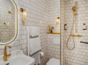 a white tiled bathroom with a shower and a sink at Hotel des Grandes Ecoles in Paris
