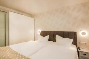 a white bed with white pillows in a bedroom at Waldsiedlung Waldhaus App 2.2 in Korswandt