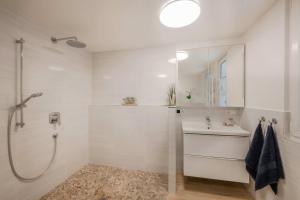 a white bathroom with a shower and a sink at Waldsiedlung Waldhaus App 2.2 in Korswandt +16 photos