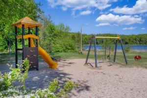 a playground with two swings and a slide at Waldsiedlung Waldhaus App 2.2 in Korswandt
