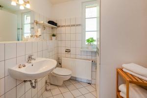 a white bathroom with a sink and a toilet at Waldsiedlung Waldhaus App 4.2 in Korswandt +20 photos