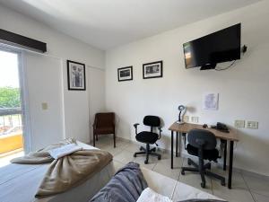 a living room with a desk and a tv on the wall at Flat em Frente a USP - Centrinho - CPO - Sem Garagem in Bauru