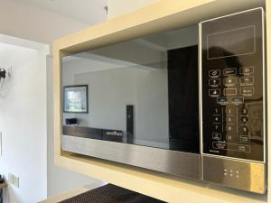 a microwave oven sitting on top of a shelf at Flat em Frente a USP - Centrinho - CPO - Sem Garagem in Bauru