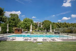 a large swimming pool with chairs and umbrellas at Agriturismo Borgo di Calmasino in Bardolino