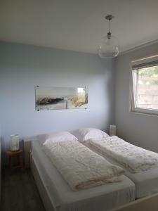 a white bedroom with two beds and a window at Strandhuis De Bakkeete B in Kamperland