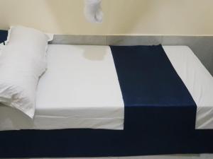 a bed with white and blue sheets and pillows at Mtomo vision in Mtwapa