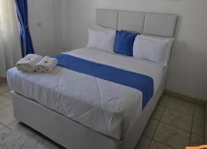a white bed with blue and white sheets and pillows at Mtomo vision in Mtwapa