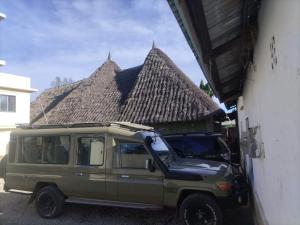 a green van parked next to a building with a thatch roof at Mtomo vision in Mtwapa