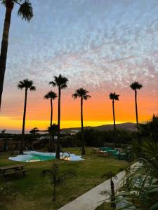 a sunset over a resort with palm trees and a pool at Wawa Tarifa in Tarifa