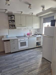 a kitchen with white cabinets and white appliances at lillstugan in Avesta