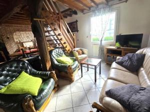 a living room with two couches and a tv at Le p'tit bourquin in Bourg-Fidèle