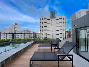 a balcony with two chairs and a pool on a building at Hub by Hosppedar in Cabedelo