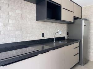 a kitchen with white cabinets and a black counter top at Hub by Hosppedar in Cabedelo