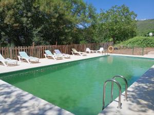 a swimming pool with chaises and chairs next to a fence at Hotel Rural Porta Coeli - Dehesa Santa Lucía in San Martín del Castañar