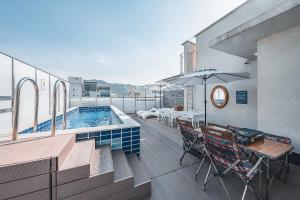 a balcony with a pool and tables and chairs at Hotel Coolstay Lions Park Daegu February Hotel Lions Park in Daegu