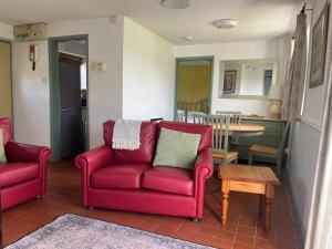 a living room with two red chairs and a table at Wren Cottage in Cowbridge