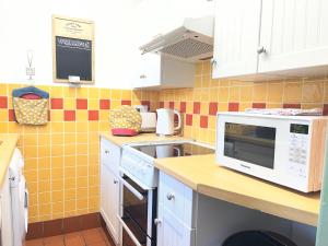 a kitchen with white cabinets and a microwave at Wren Cottage in Cowbridge
