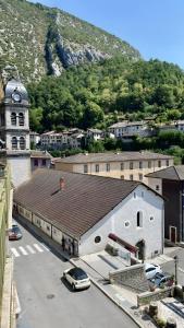 a large white building with a clock tower next to a street at Casa d'Eva in Pont-en-Royans +7 photos