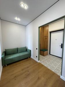 a living room with a green couch and a door at NewCityLife in Astana