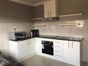 a kitchen with white cabinets and a black appliance at Leeba Apartments in Maseru