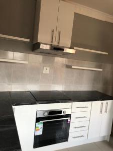 a kitchen with white cabinets and a black oven at Leeba Apartments in Maseru +5 photos
