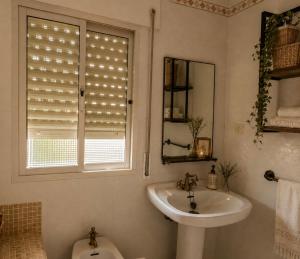 a bathroom with a sink and a window and a toilet at Casa Abuela Dolores in Setenil